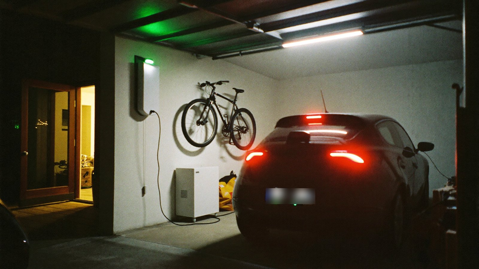 Električni auto na punjenju u garaži uz kućnu bateriju – potrošnja koju cijena struje 2026 naplaćuje 35 % skuplje iznad praga